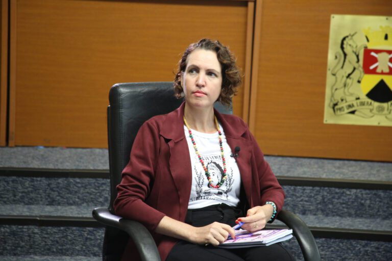 Vereadora Fernanda Garcia está sentada no plenário da Câmara, com o brasão do Poder Legislativo aparecendo atrás dela. Ela questiona o abandono da saúde em Sorocaba