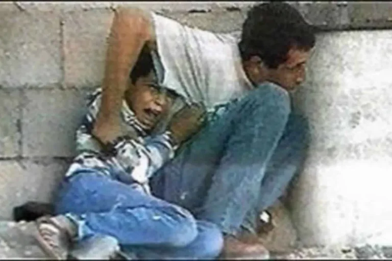 Imagem mostra a Muhammad al Dura, criança palestina de apenas 12 anos, e seu pai Jamal al Dura, tentando proteger seu filho dos tiros das tropas israelenses. Mesmo desarmados e indefesos, eles foram fuzilados pelo exército de Israel sob as filmages da imprensa